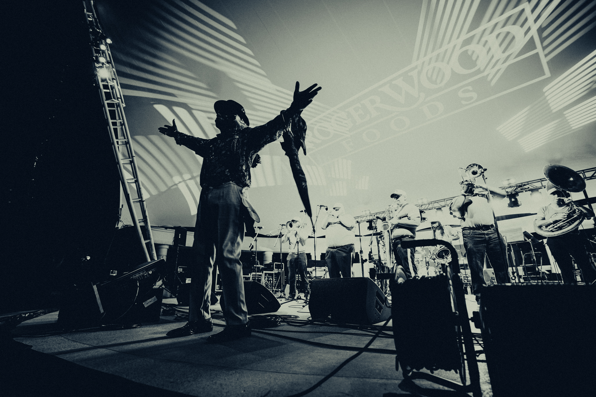 Brass band onstage with a silhouetted performer holding his arms wide